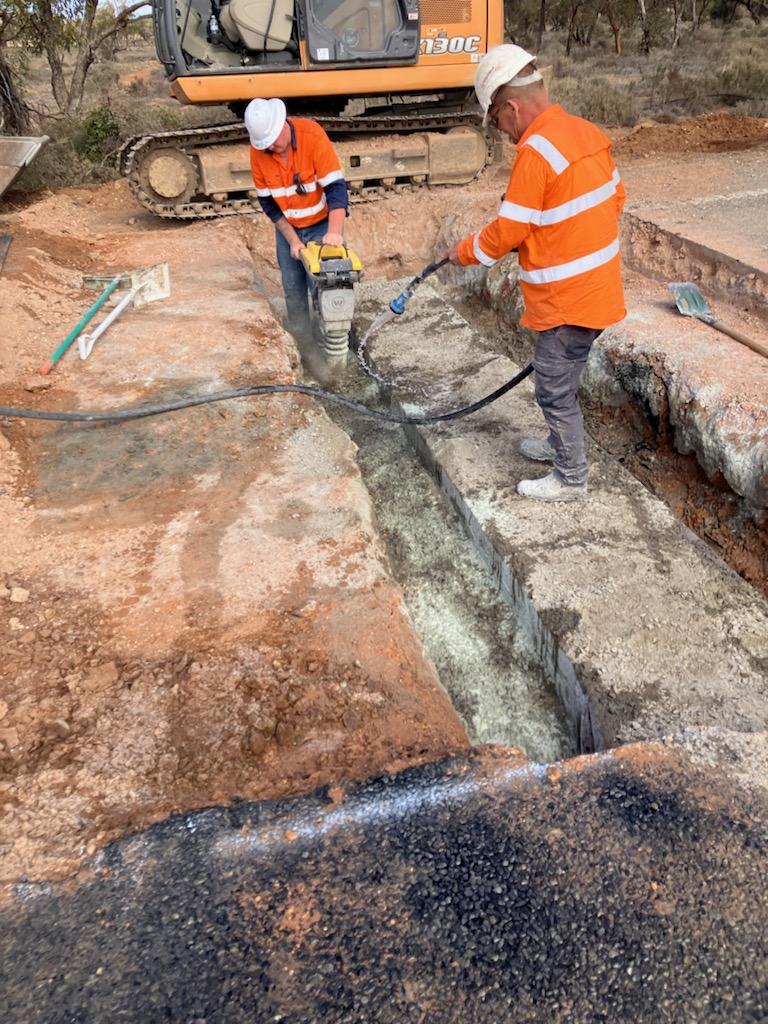 Workers on a culvert drainage project with excavator