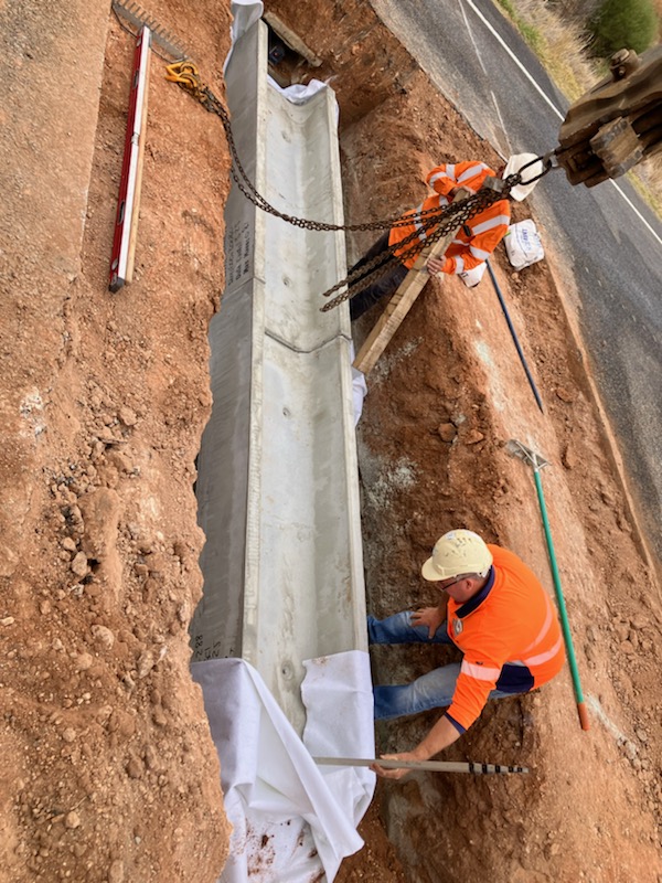 Workers placing a precast culvert section